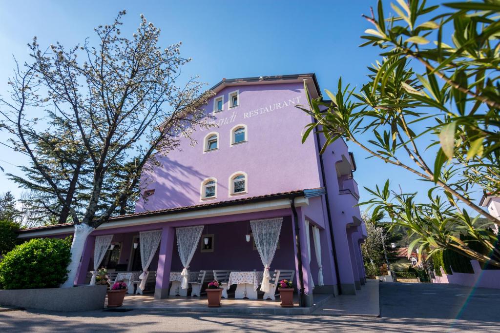 un edificio púrpura con árboles delante de él en Hotel Villa Sandi - free parking, en Čavle