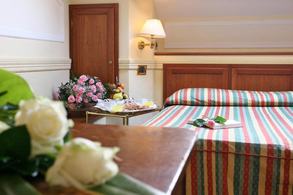 a hotel room with a bed and a table with flowers at Hotel Arlecchino in Venice