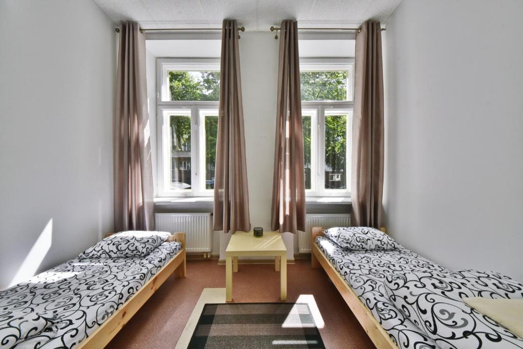 a bedroom with two beds and two windows at Laisves Avenue Hostel "Easy Kaunas" in Kaunas