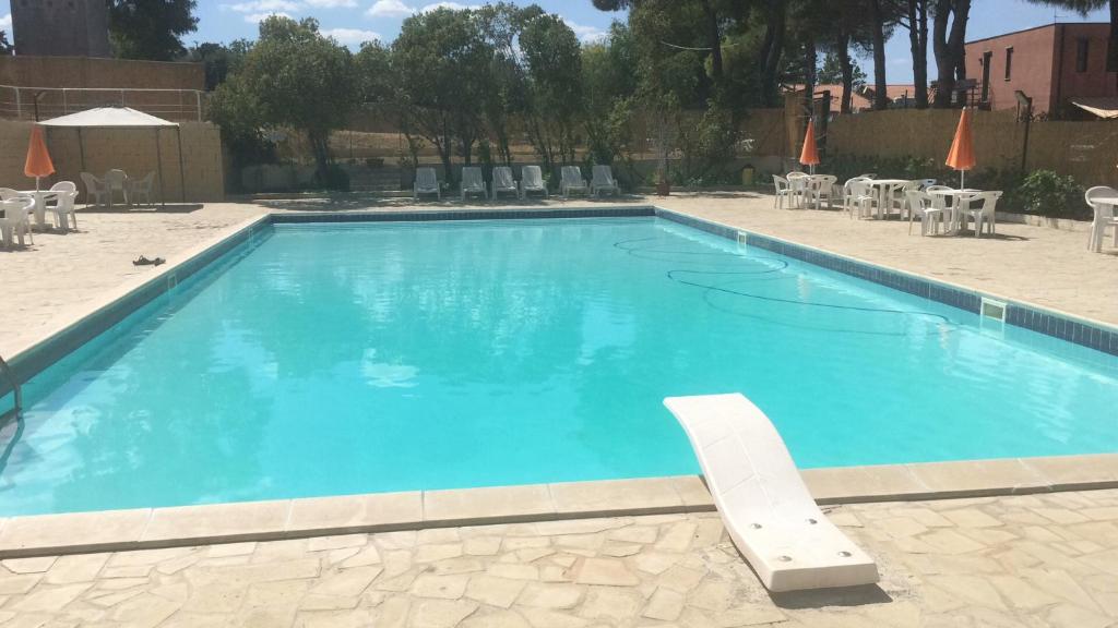 une grande piscine bleue avec des chaises et des tables dans l'établissement Le Ville 1 Costa Saracena, à Agnone Bagni