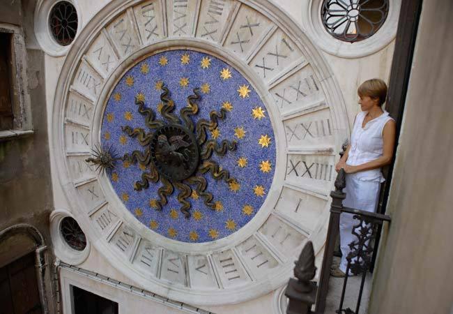 une femme debout sur un escalier à côté d'une horloge dans l'établissement Best Windows, à Venise