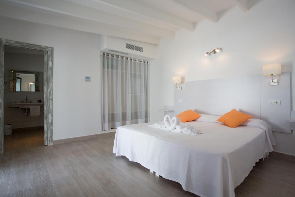 a white bedroom with a white bed with orange pillows at Hotel Rosamar - Emar Hotels in Es Pujols