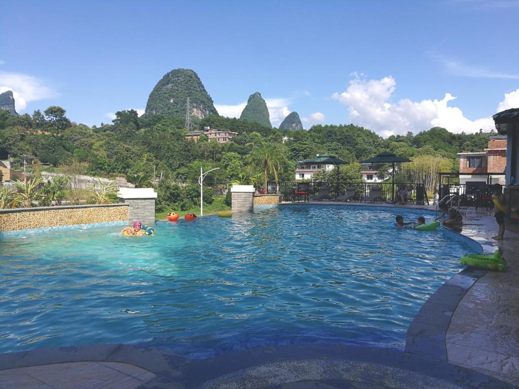 a group of people swimming in a swimming pool with mountains at The Bamboo Leaf Yangshuo in Yangshuo