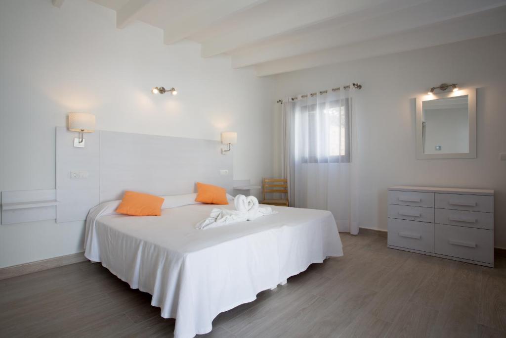 a white bedroom with a white bed with orange pillows at Hotel Rosamar - Emar Hotels in Es Pujols