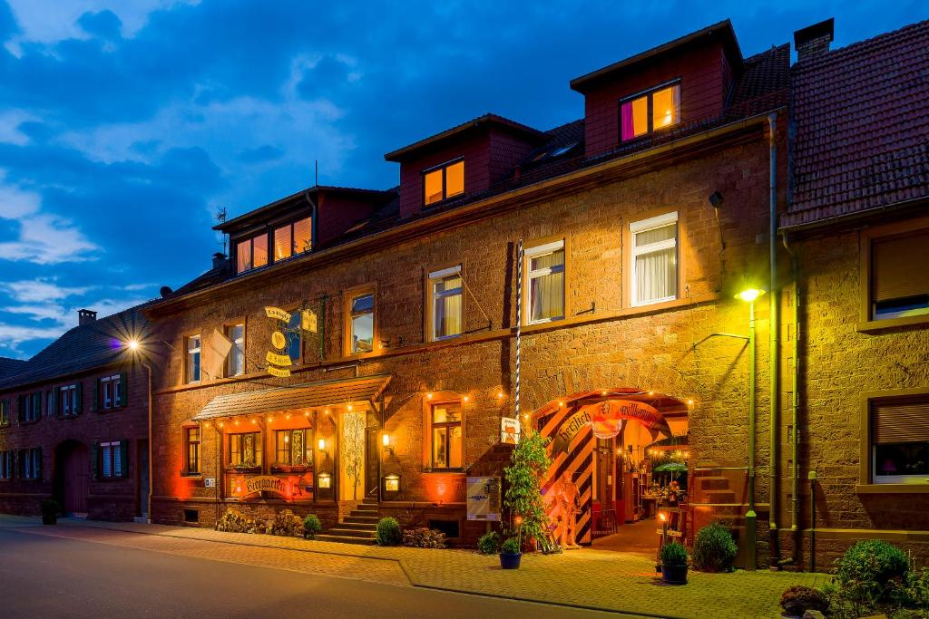 ein großes Backsteingebäude in der Nacht mit Lichtern in der Unterkunft Gasthaus & Hotel Drei Lilien in Werbach