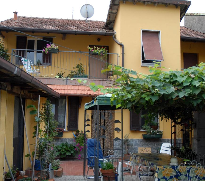 Casa amarilla con balcón y patio en rosso melograno, en Bareggio