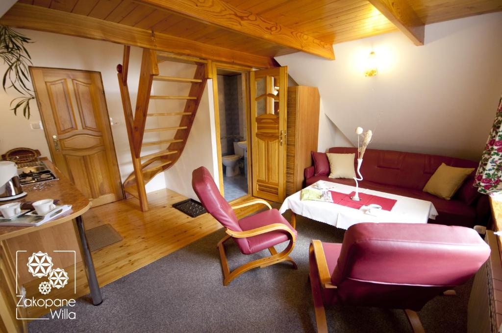 a living room with a red couch and a bed at Zakopane Willa in Zakopane