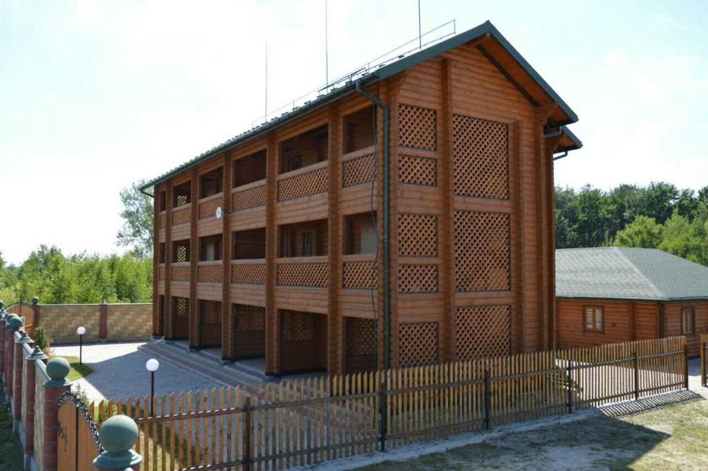 un gran edificio de madera con una valla delante en Pulemchanka, en Pulemets