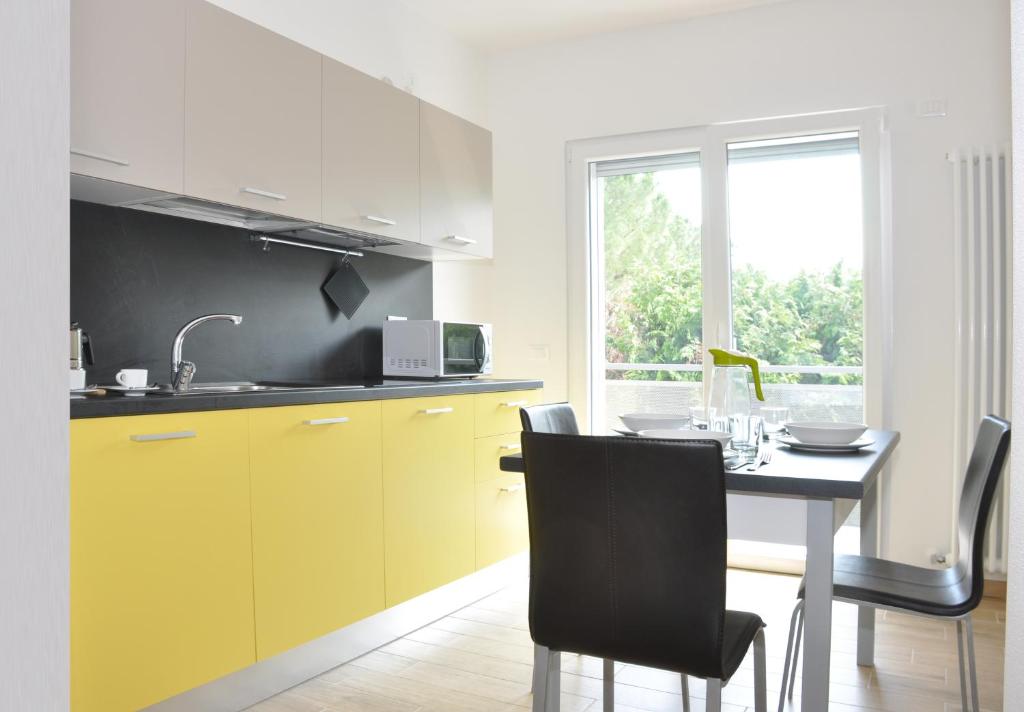 a kitchen with yellow cabinets and a table with chairs at Easy & Modern in Arco