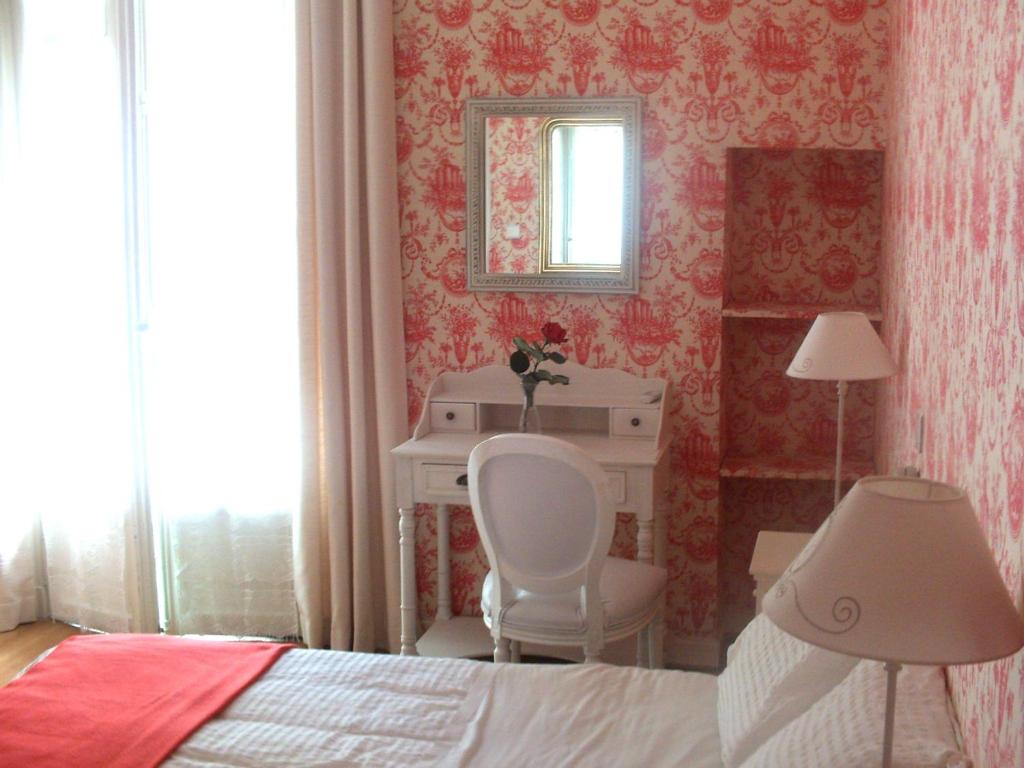 a bedroom with a bed and a desk and a mirror at Hotel Villa Rivoli in Nice