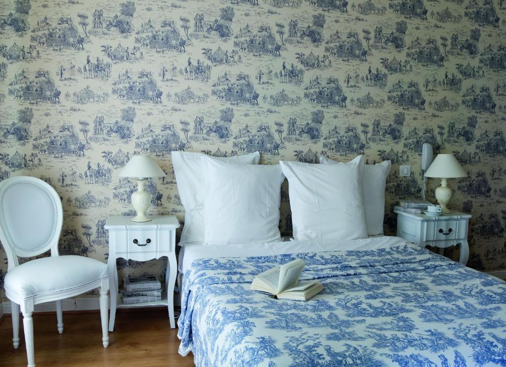 a bedroom with a bed with a book and a chair at Hotel Villa Rivoli in Nice