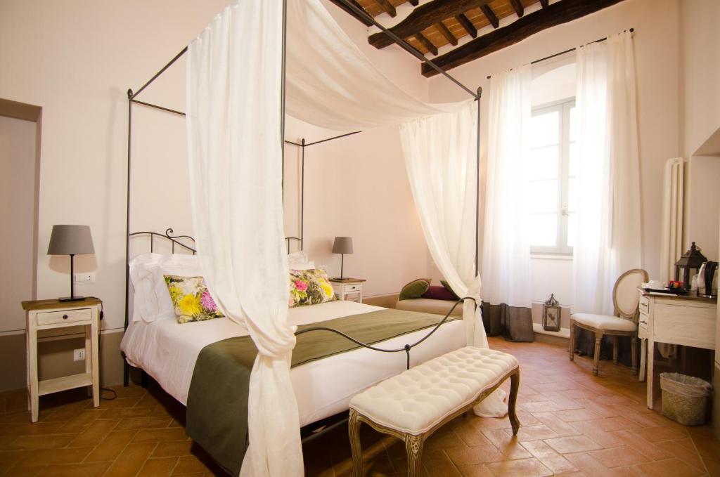 a bedroom with a canopy bed with a bench and a window at Dimora Dell'Erbe Rooms in Montepulciano