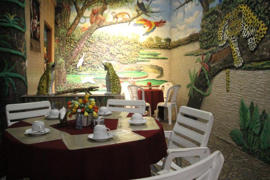 una mesa y sillas en un restaurante con un mural en Hotel Marajoara, en Belém