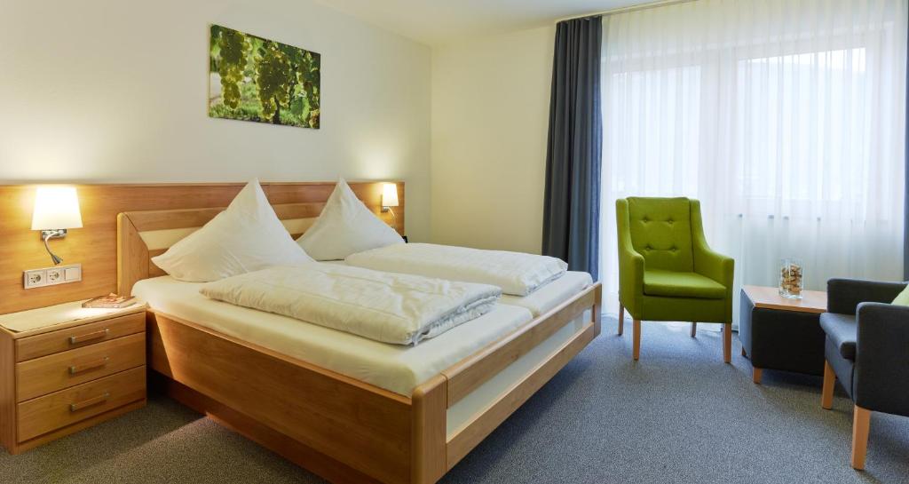 a bedroom with a bed and a green chair at Weinhaus am Schieferfels in Veldenz