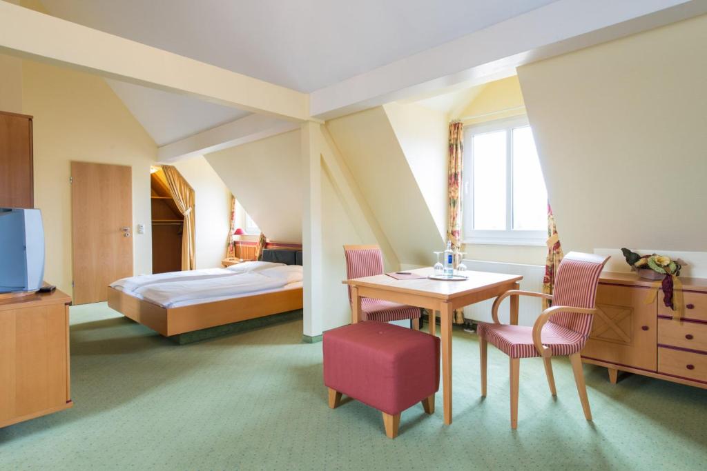 Habitación de hotel con cama, mesa y sillas en Hotel Eisbach en Ransbach-Baumbach