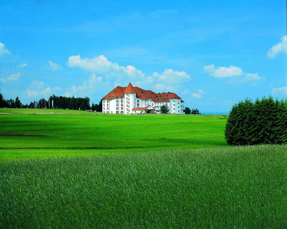 a large white building on a green field with a house at Kurhotel Leonardo in Gmünd