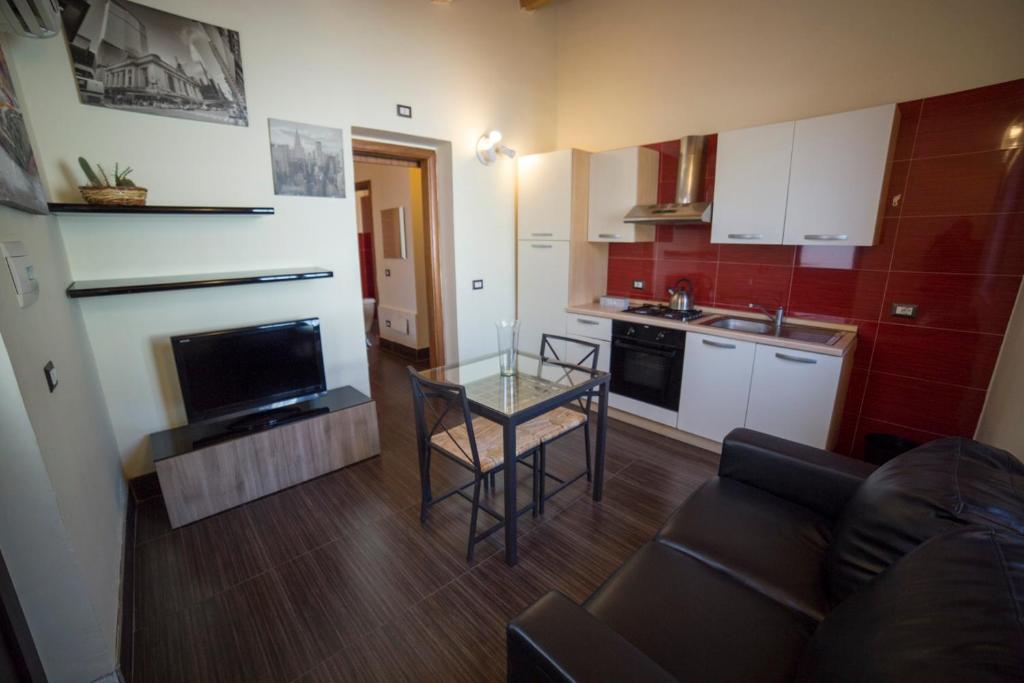 ein Wohnzimmer mit einem Tisch und einer Küche in der Unterkunft Red Orange Catania Ognina in Catania