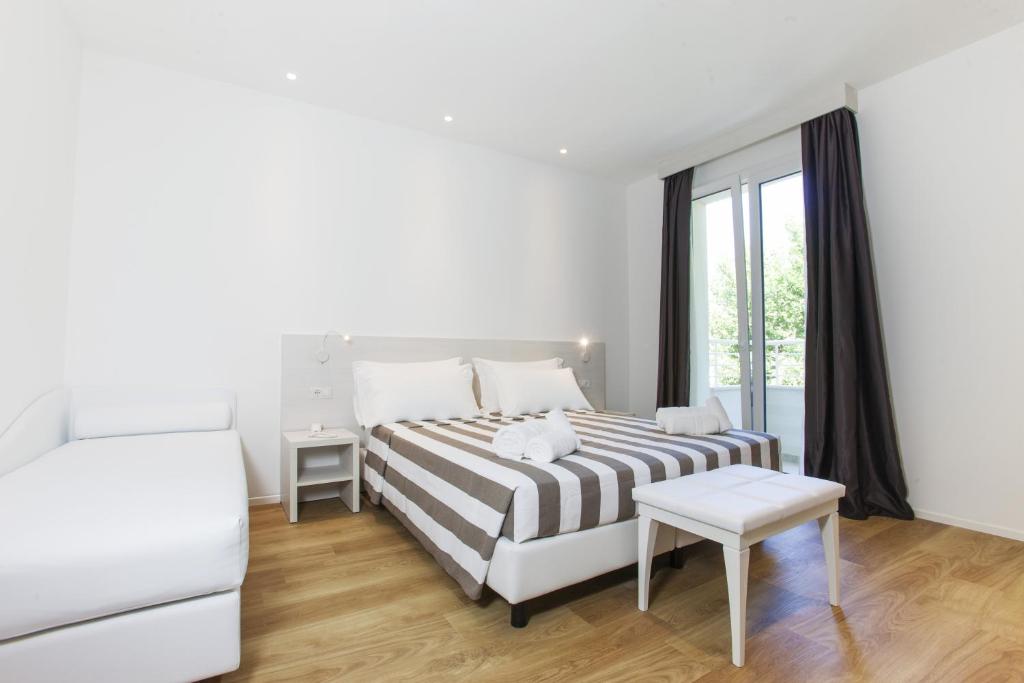 a white bedroom with a bed and a window at Hotel Houston Suites in Rimini