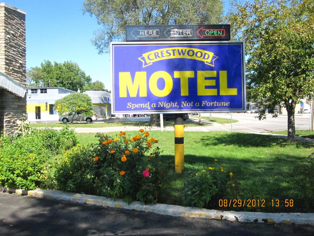 a sign for a motel with flowers in a yard at Crestwood Motel in Burlington