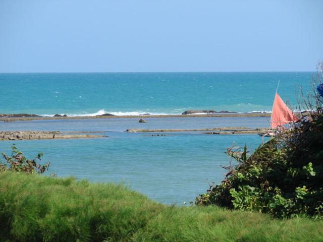 a red sail boat in a body of water at Muro Alto Marupiara Flats in Porto De Galinhas