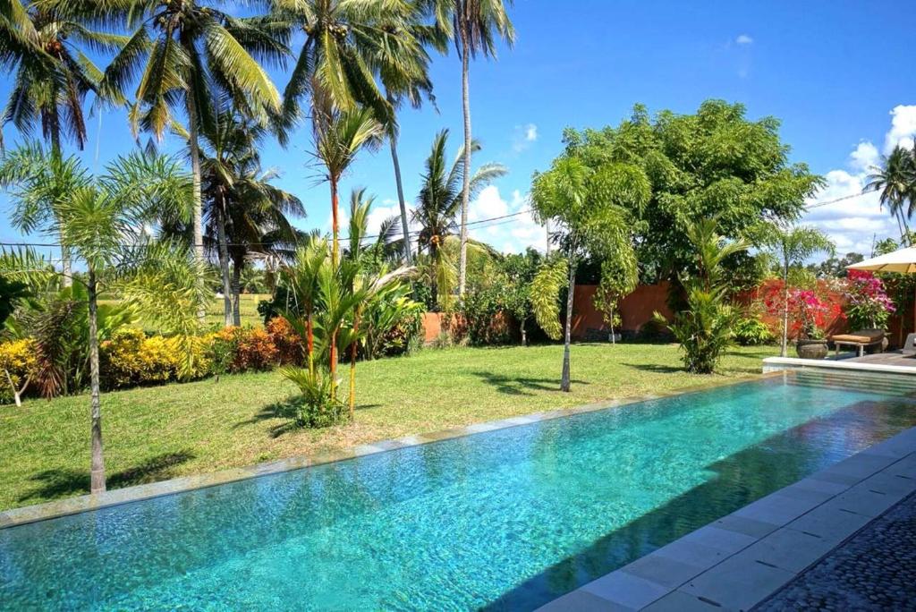 a swimming pool in a resort with palm trees at Villa Taman Kanti in Ubud