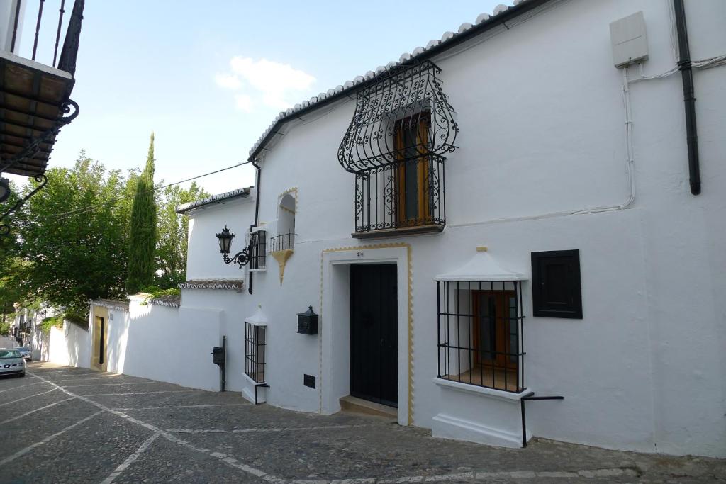 a white building with a door and a balcony at Salvatierra Guest House in Ronda