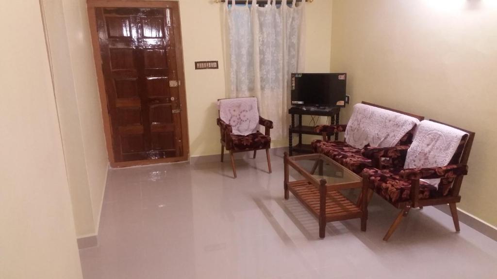 a living room with two chairs and a tv at Able Homestay in Thekkady