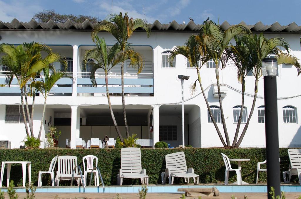 a hotel with chairs and palm trees in front of it at Hotel Nuar in Betim