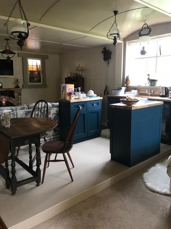 uma cozinha com armários azuis e uma mesa e cadeiras em Log cabin em Armagh