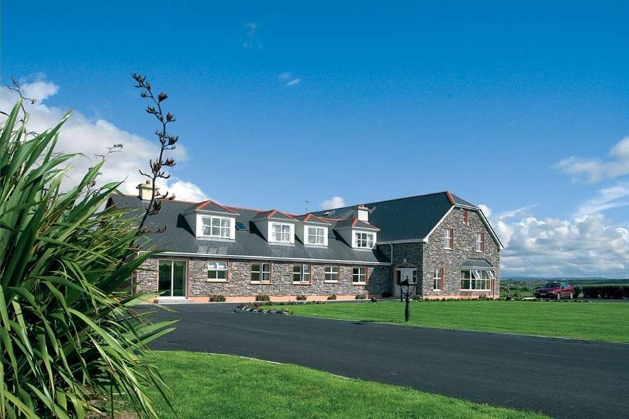 une grande maison en briques avec une pelouse verte dans l'établissement Cashen Course House, à Ballybunion