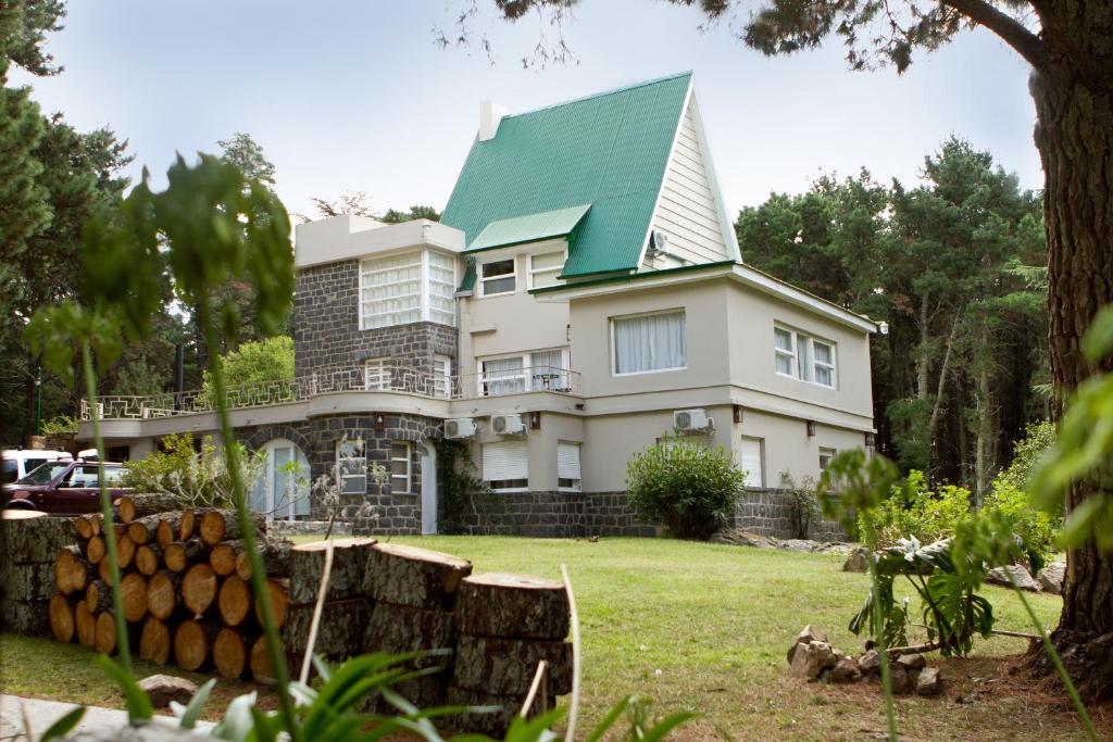 uma grande casa branca com um telhado verde em Hosteria Mi Casa en la Sierra em Tandil