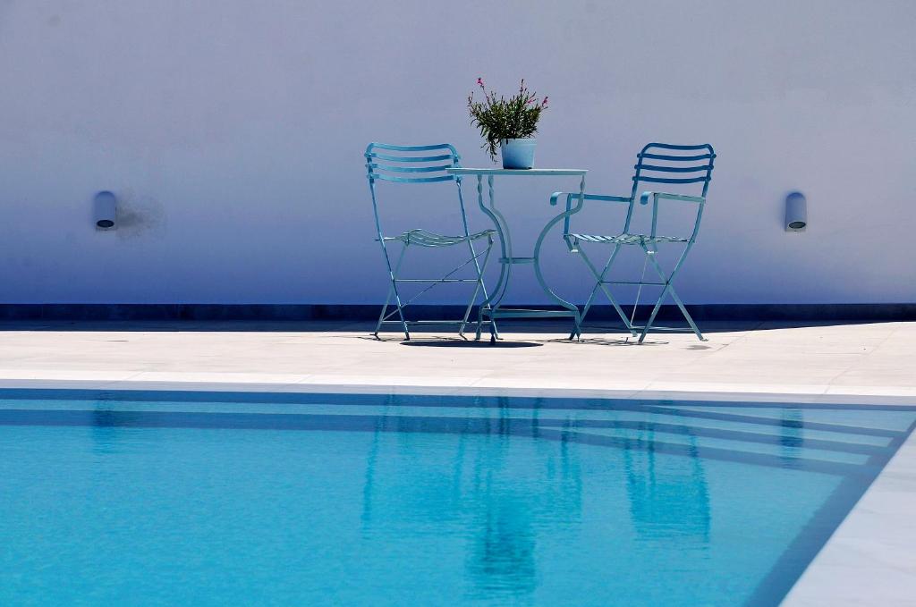 two chairs and a table with a potted plant next to a pool at Ionathan Koufonisia Suites in Koufonisia