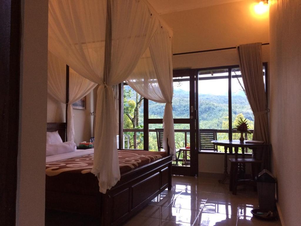 a bedroom with a canopy bed with a view at Made Oka Homestay and Warung in Munduk