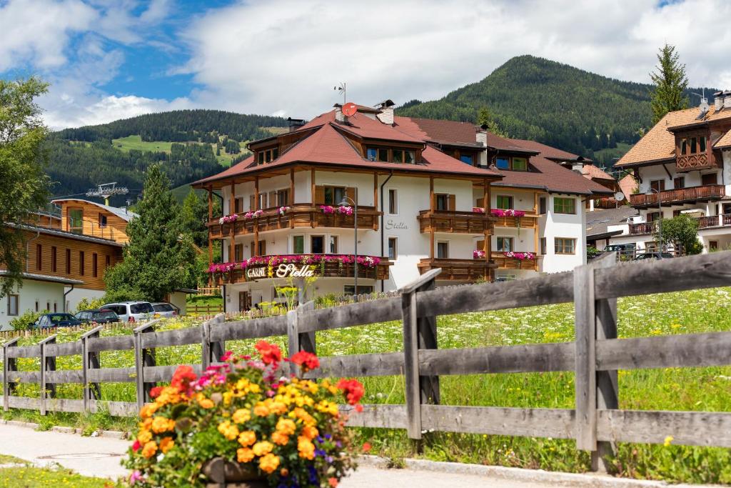 una casa en las montañas con una valla y flores en Residence Garni Stella en San Vigilio Di Marebbe