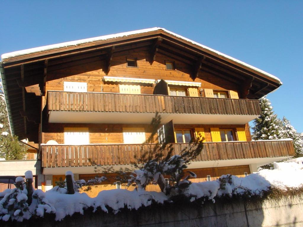 um grande edifício de madeira com uma varanda na neve em Chrinnengletscher em Grindelwald