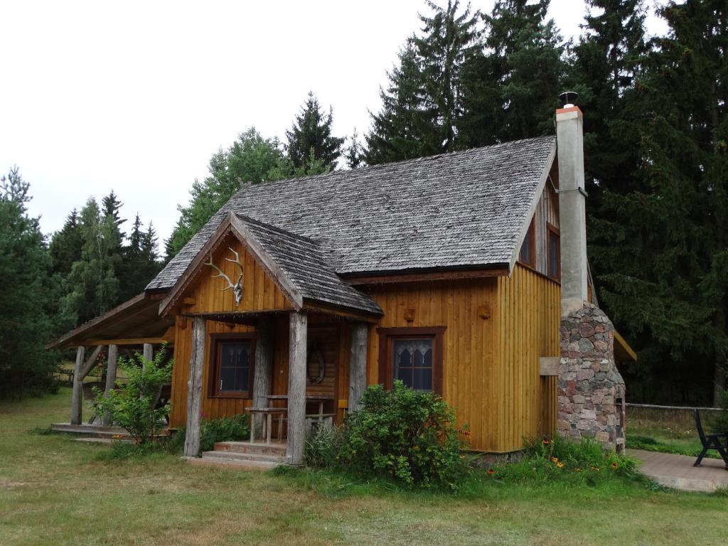 une petite maison en bois avec une cheminée sur un champ dans l'établissement Dworek Telimena, à Smolniki