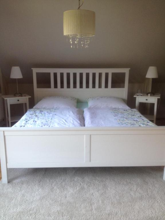 a white bed in a bedroom with two tables at FeWo Fleckeby an der Schlei in Fleckeby