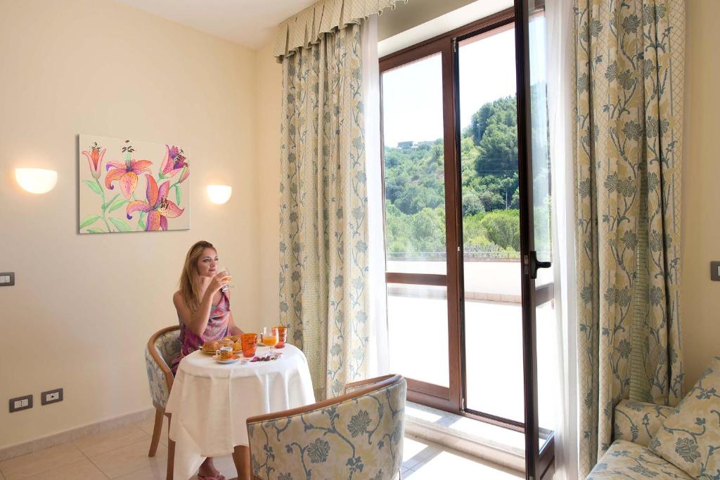 una mujer sentada en una mesa en una habitación con ventana en Albergo Terme Forlenza, en Contursi Terme