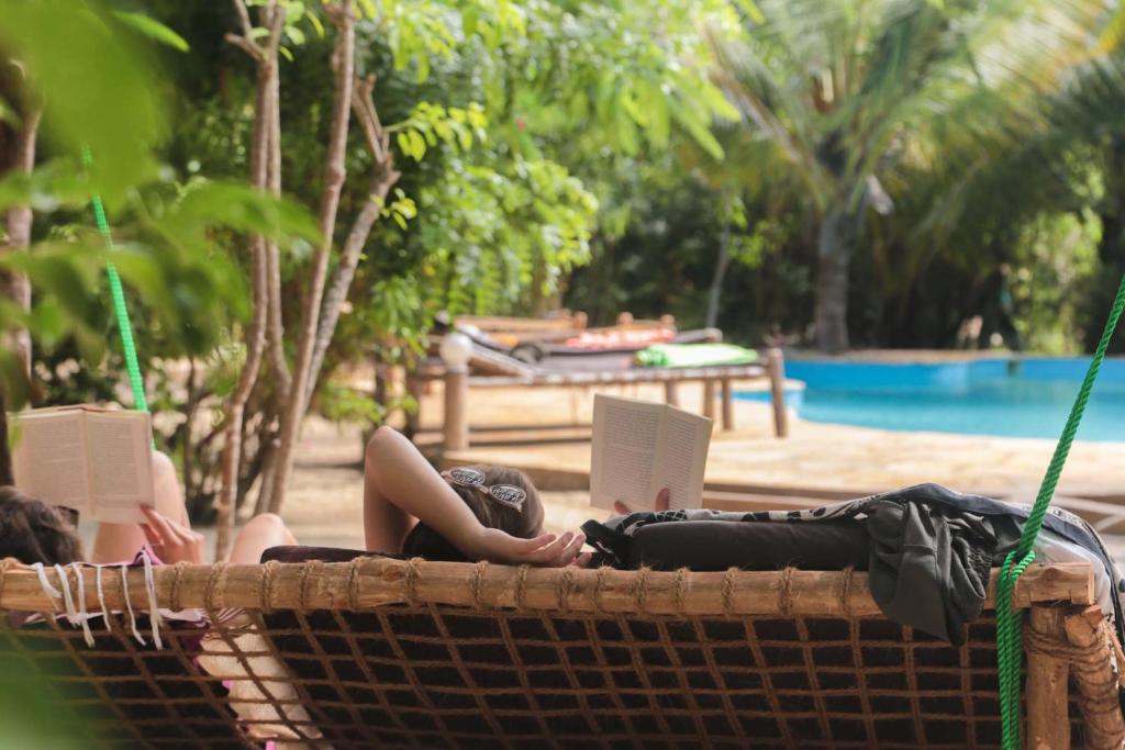 a woman laying in a hammock with a laptop at Demani Lodge Zanzibar in Paje