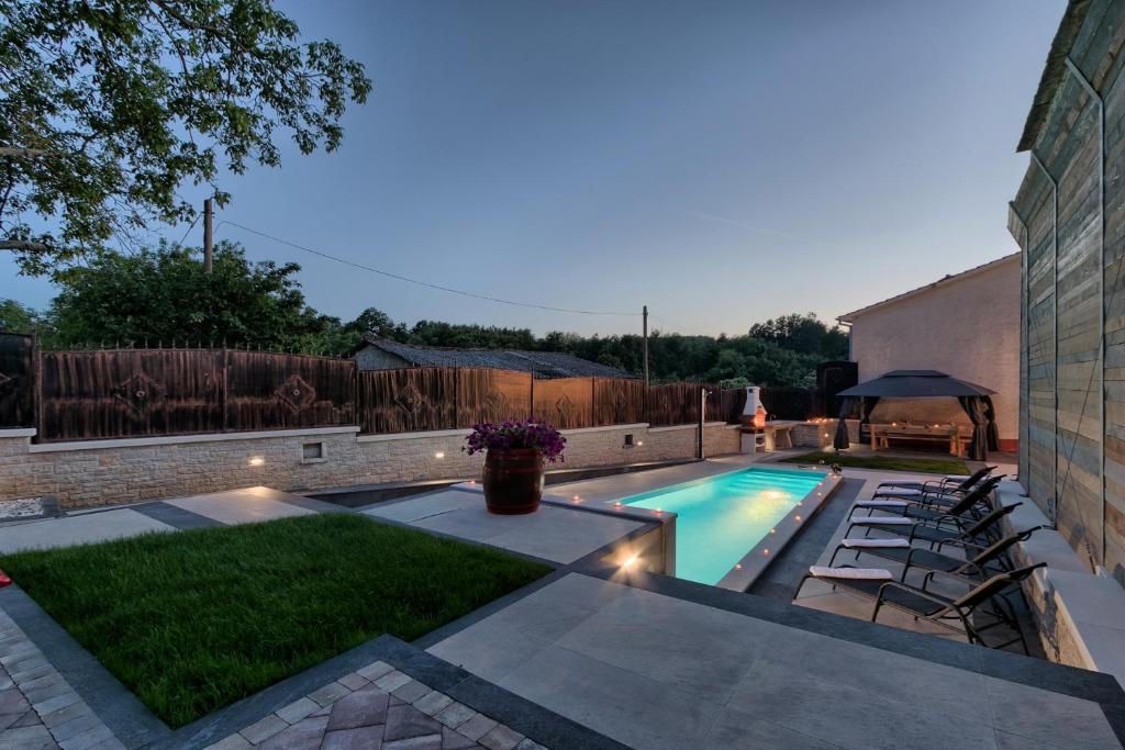 a backyard with a swimming pool with chairs and a table at Villa Patrick-Luxury stone house in the center of Istria in Pazin