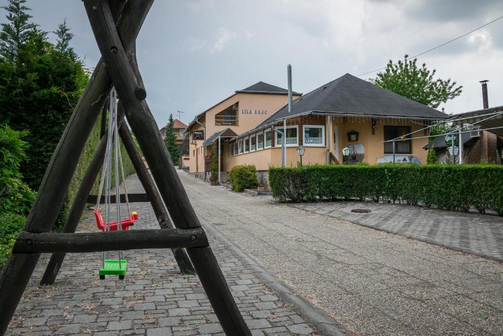 a swing with a green toy on a brick street at Lila Akác Vendégház Esztergom in Esztergom