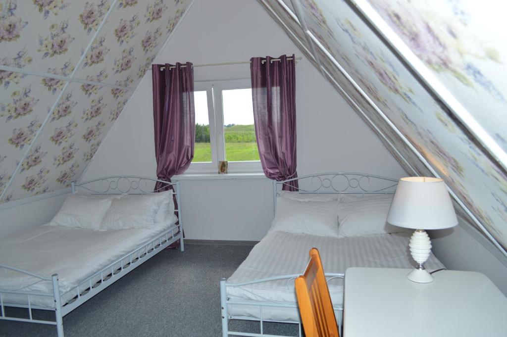 Zimmer mit 2 Betten, einem Tisch und einem Fenster in der Unterkunft Chata Dziadka Ignacego in Augustów