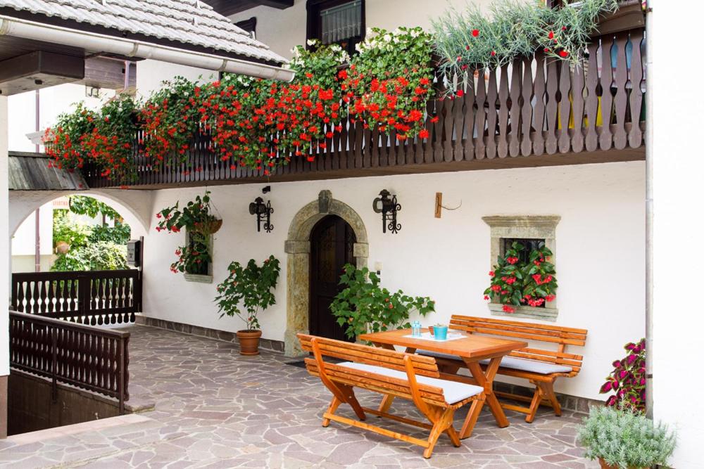 a patio with two benches and a table and flowers at Apartments Dolar in Bled