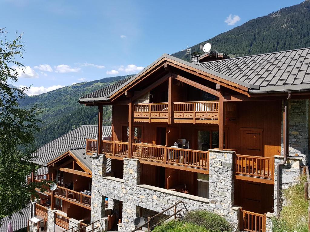 a log cabin with a deck and mountains in the background at Arpege Des Neiges in Sainte-Foy-Tarentaise
