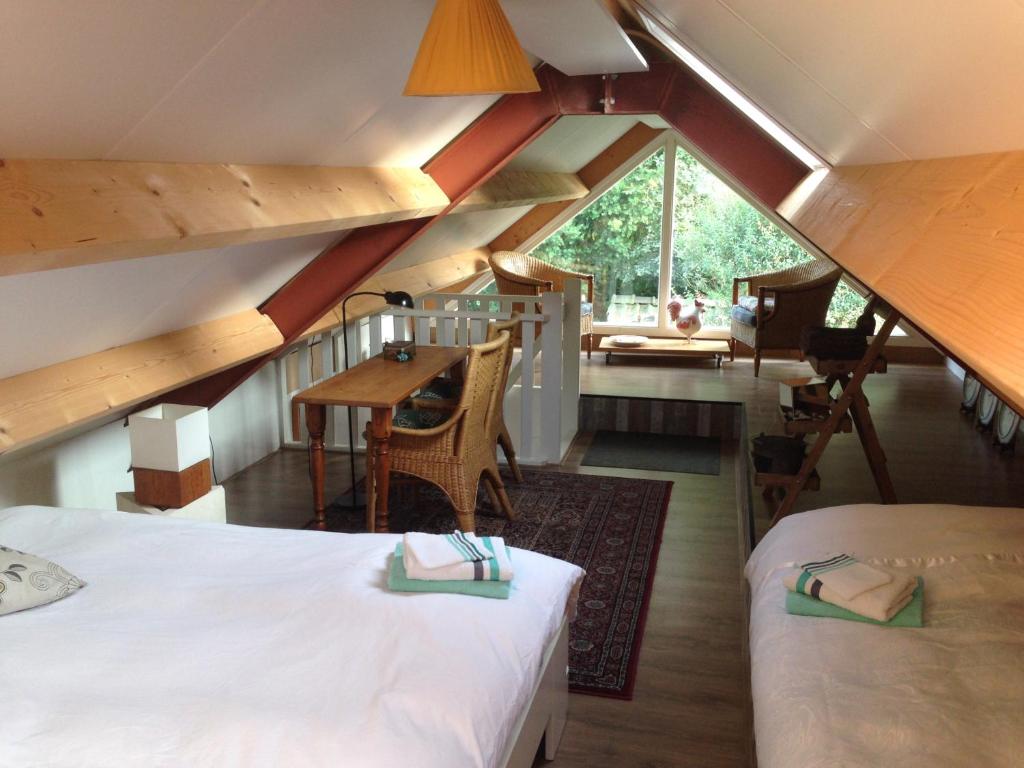 een zolderkamer met 2 bedden en een tafel bij B&B Vroomm in Helvoirt