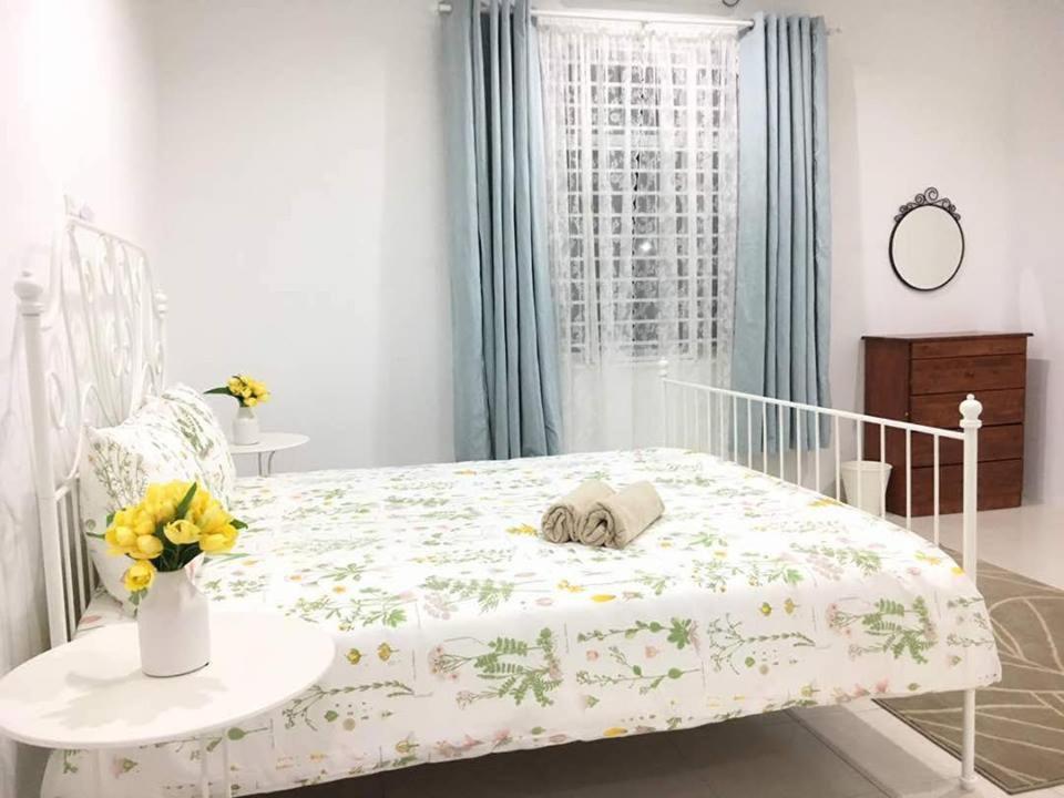 a white bed in a room with a vase of flowers at Ceri Merah Homestay in Kuantan