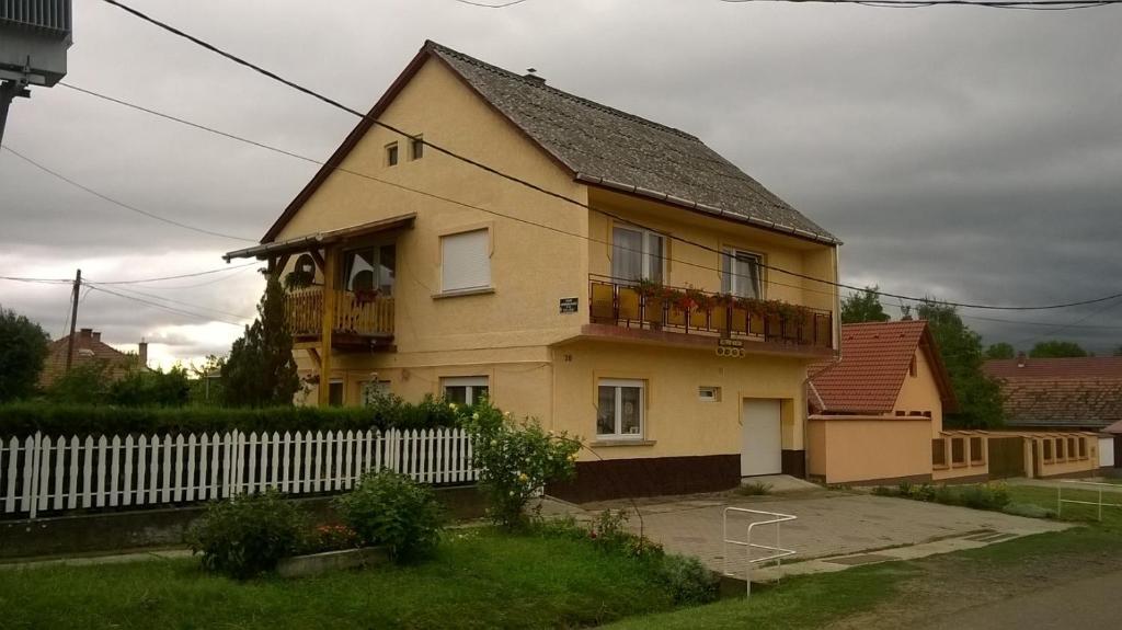 ein gelbes Haus mit einem weißen Zaun davor in der Unterkunft Keletifény Vendégház in Verpelét