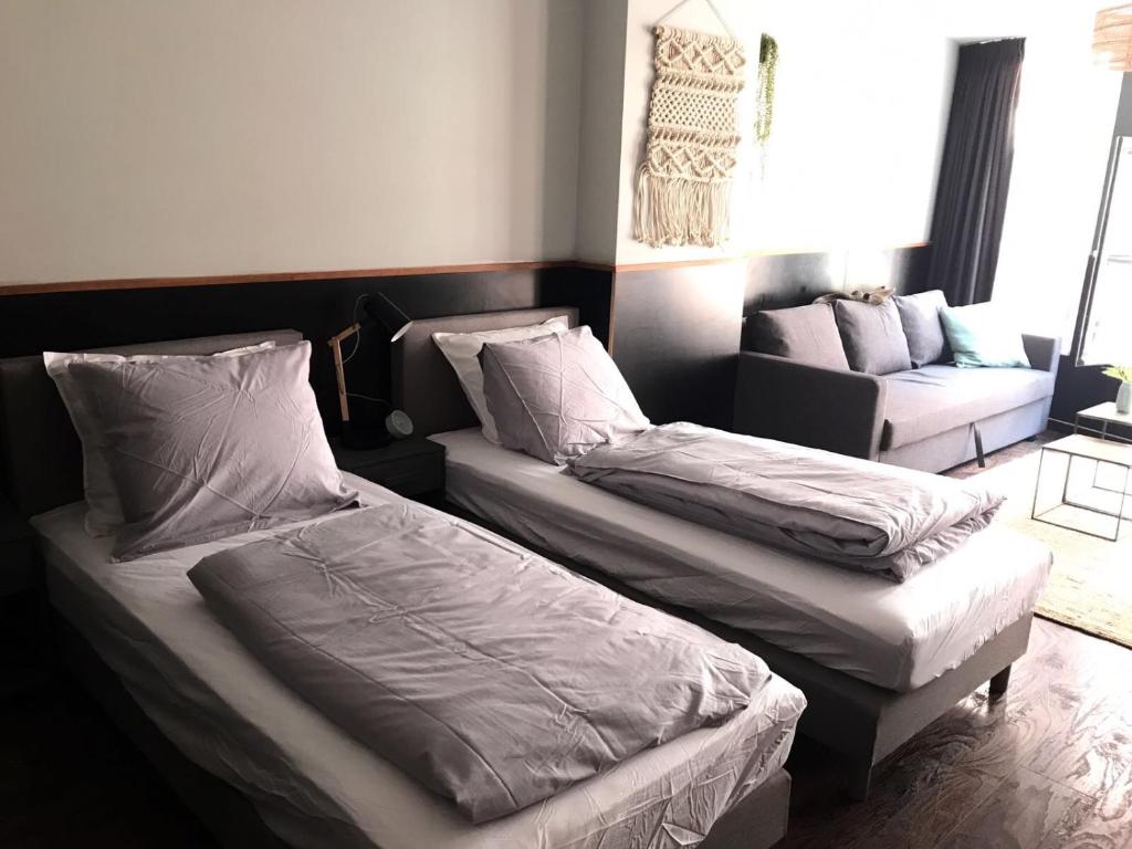 2 camas en una habitación con sofá en Amsterdam Red Light Bed & Breakfast en Ámsterdam