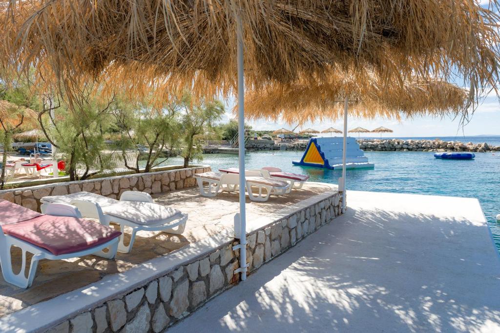 a patio with chairs and tables and a straw umbrella at Holiday Park Mandrice in Mandre
