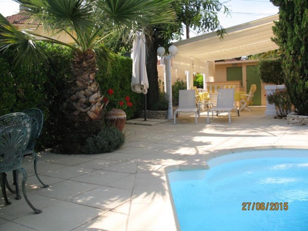 een patio met een zwembad en een tafel en stoelen bij Le Belvedere in Bandol